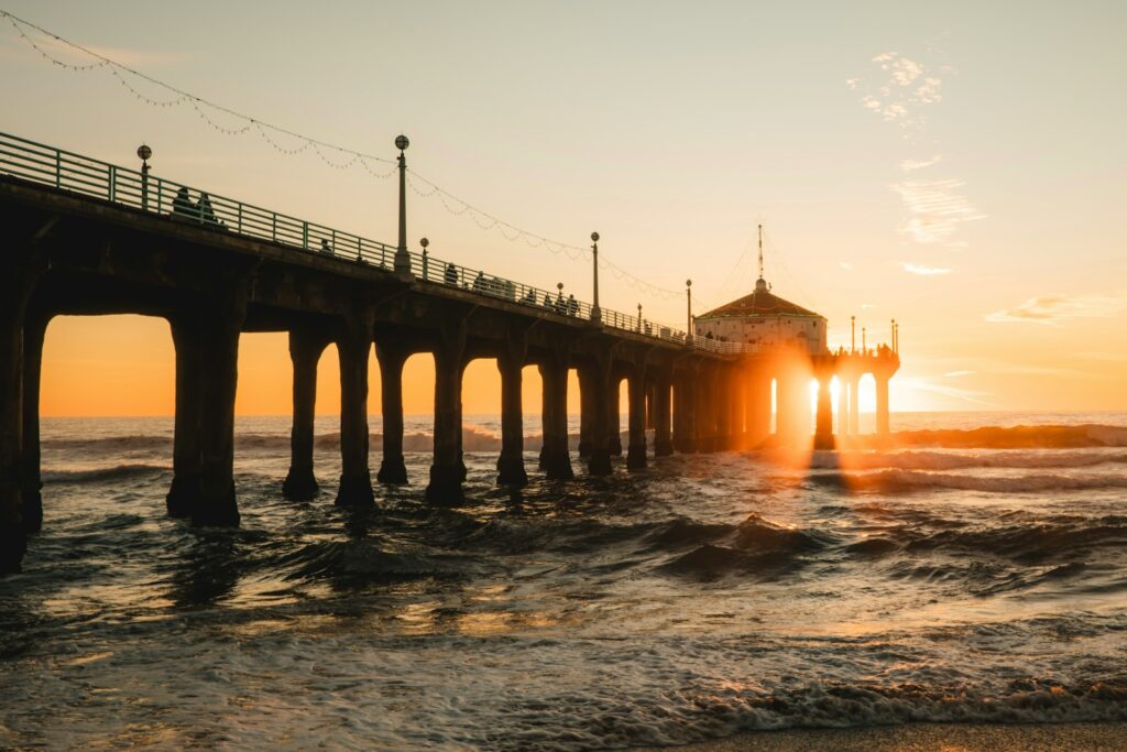 The sun is setting at the end of a pier